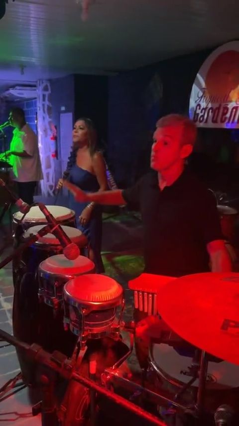 Percussionista nas congas e cantora ao microfone durante show ao vivo